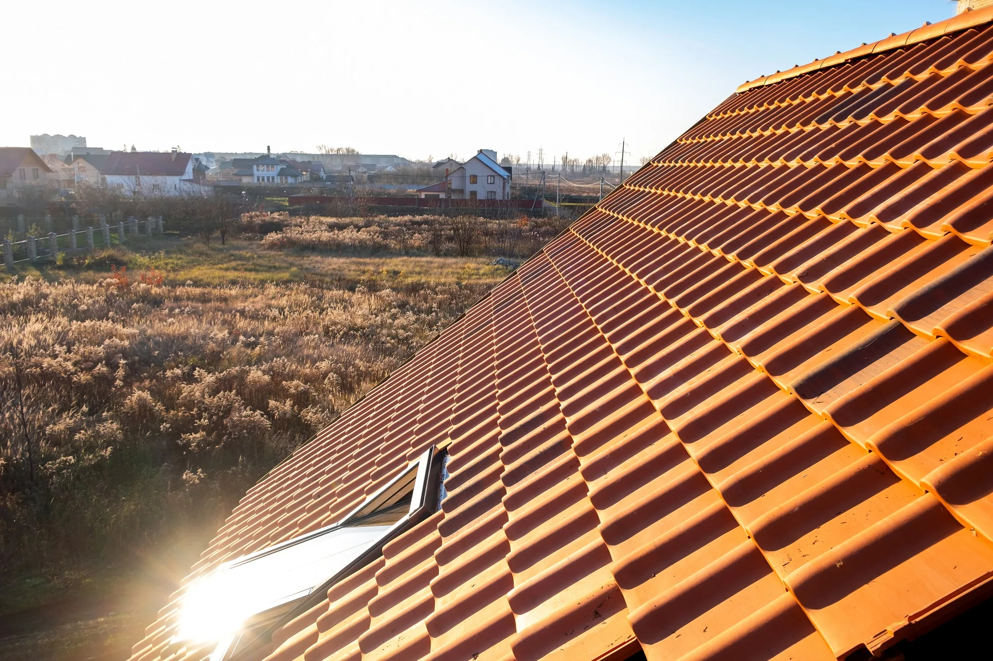 Overlapping rows of yellow ceramic roofing tiles covering residential building roof